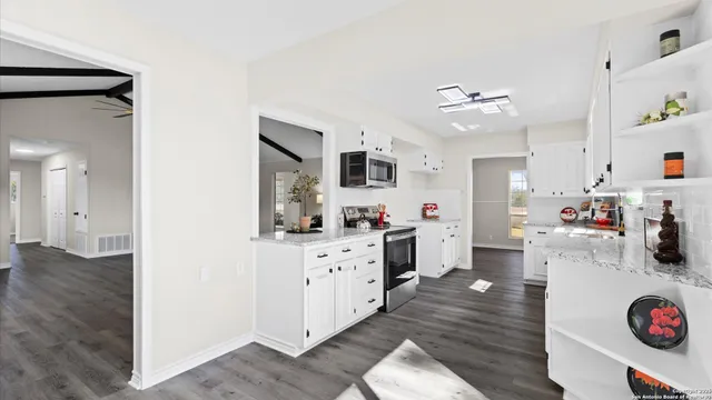 a kitchen with stainless steel appliances a stove top oven a sink dishwasher and a refrigerator with wooden floor