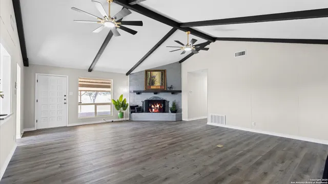a view of an empty room with wooden floor fireplace and a window