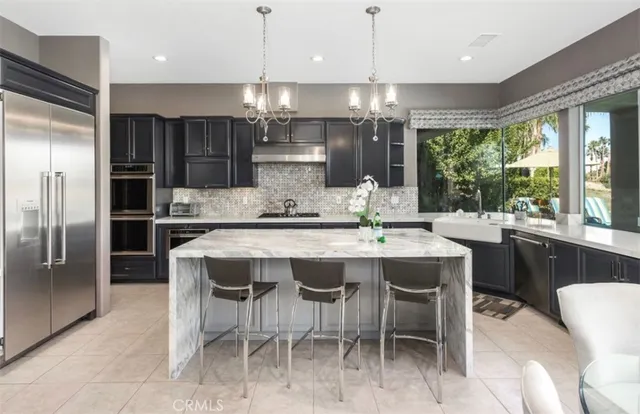 a kitchen with stainless steel appliances kitchen island granite countertop a table chairs stove and refrigerator