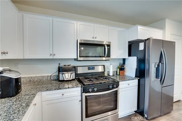 a kitchen with stainless steel appliances granite countertop a stove a refrigerator and a microwave