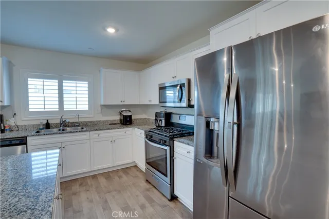 a kitchen with stainless steel appliances granite countertop a refrigerator a sink a stove and dishwasher