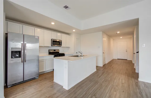 a kitchen with stainless steel appliances granite countertop a refrigerator a stove top oven a sink and dishwasher