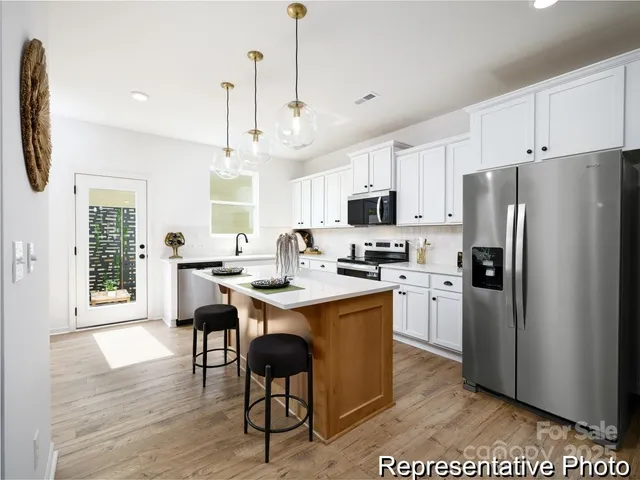 a kitchen with stainless steel appliances a dining table chairs refrigerator and sink