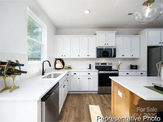 a kitchen with stainless steel appliances a sink a stove a refrigerator cabinets and a window
