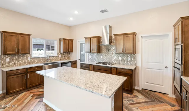 a kitchen with stainless steel appliances granite countertop a sink and a refrigerator