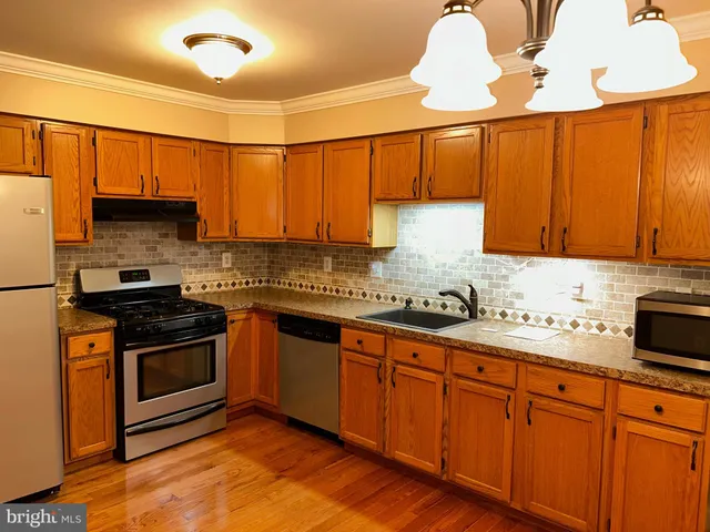 a kitchen with stainless steel appliances granite countertop wooden cabinets a stove a sink and dishwasher