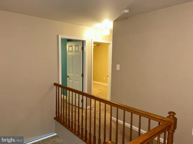 a view of a hallway with wooden floor and a bathroom