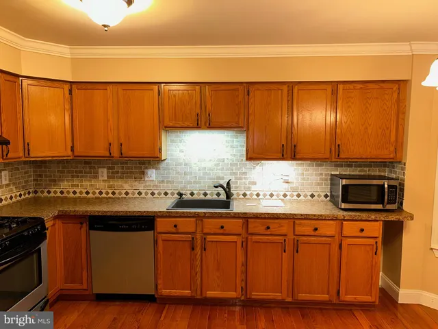 a kitchen with stainless steel appliances granite countertop a sink a stove cabinets and wooden floor