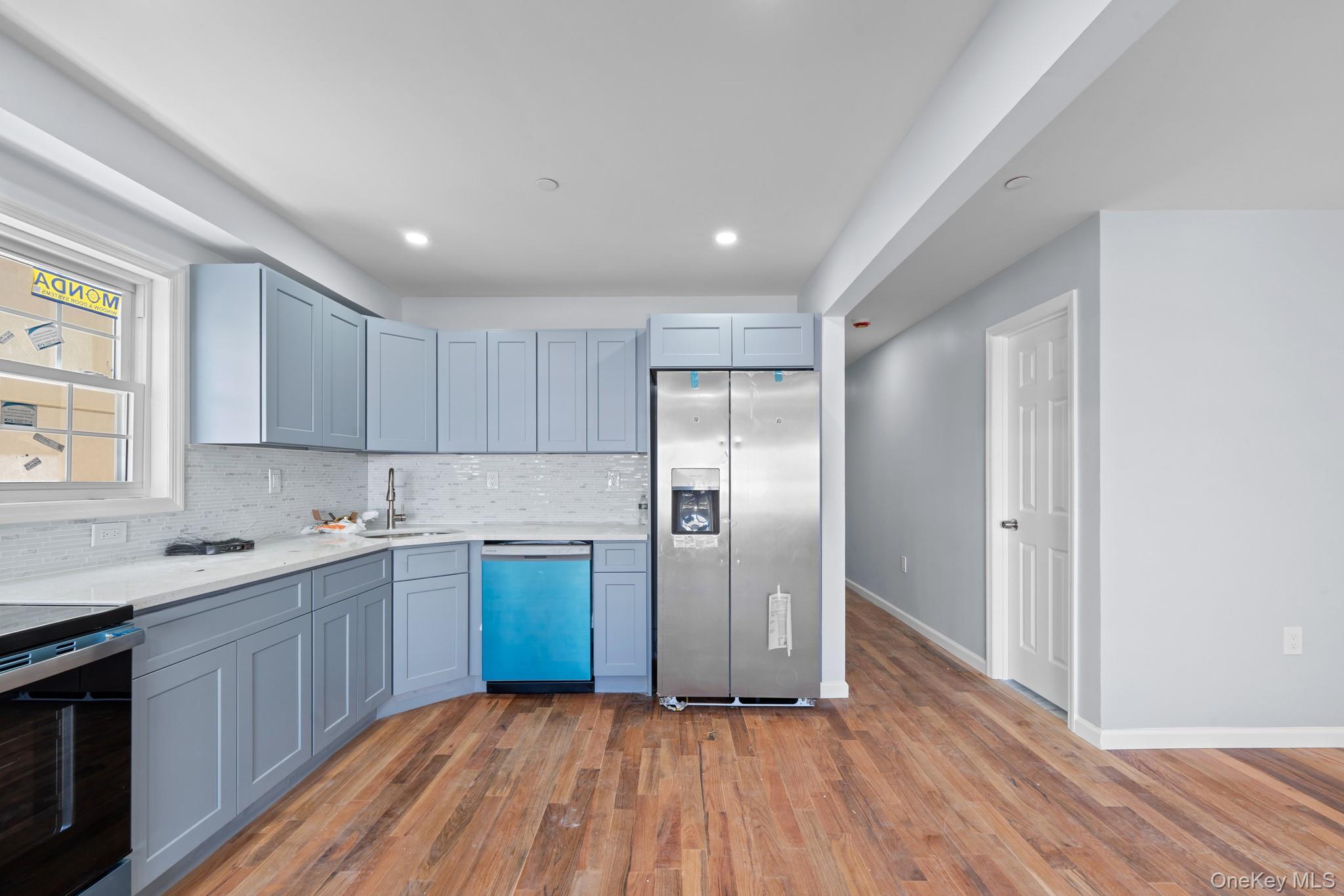 223-12 134th Road Queens, NY 11413 - Photo 3 of 17 Kitchen featuring stainless steel fridge, dark wood finished floors, decorative backsplash, dishwashing machine, and light stone counters