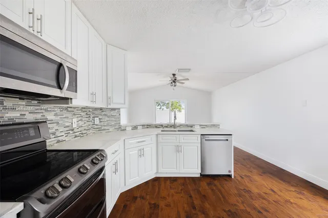 a kitchen with granite countertop a refrigerator stove and sink
