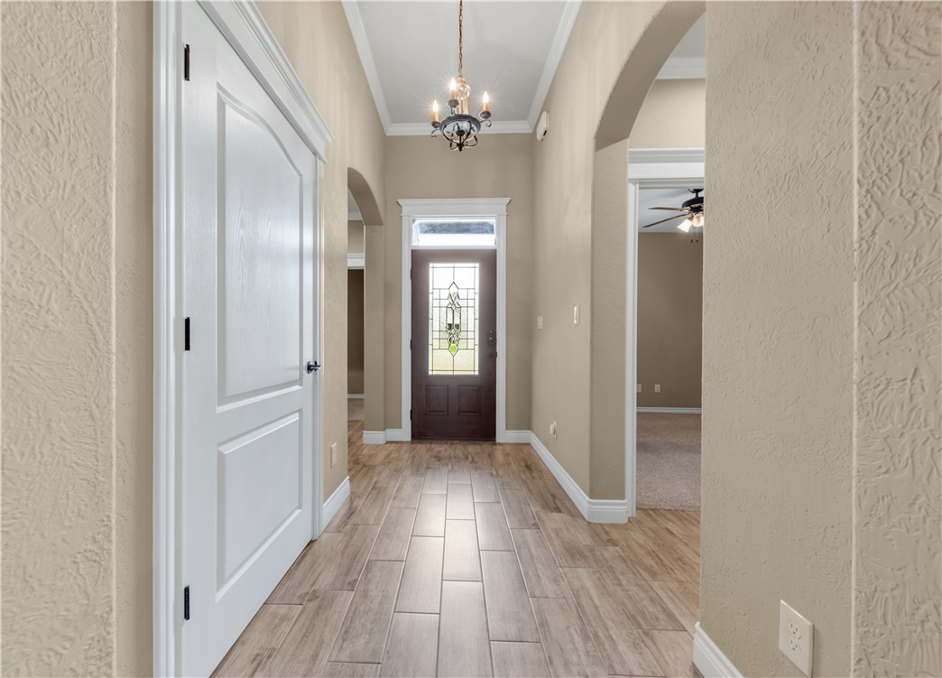3520 Foxcroft Path Bryan, TX 77808 - Photo 2 of 28 Foyer entrance with arched walkways, a textured wall, wood tiled floors, a chandelier, and ornamental molding