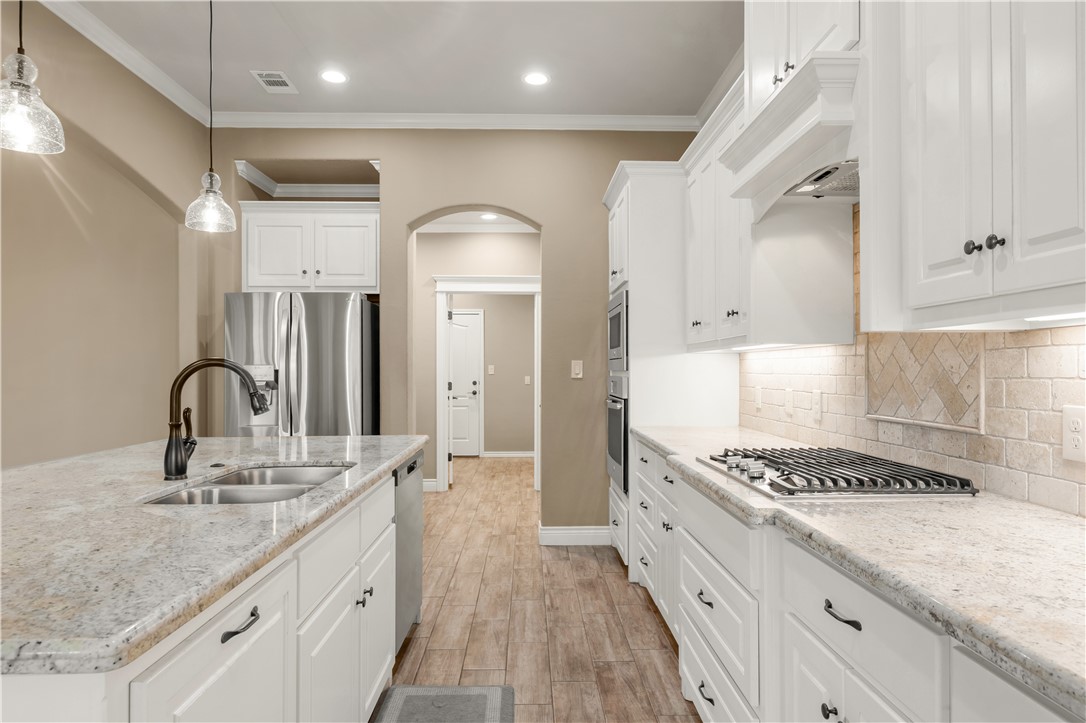 3520 Foxcroft Path Bryan, TX 77808 - Photo 9 of 28 Kitchen featuring white cabinetry, pendant lighting, appliances with stainless steel finishes, arched walkways, and ornamental molding