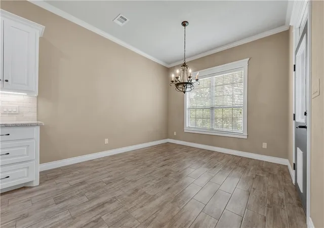 a view of an empty room with wooden floor closet and a window