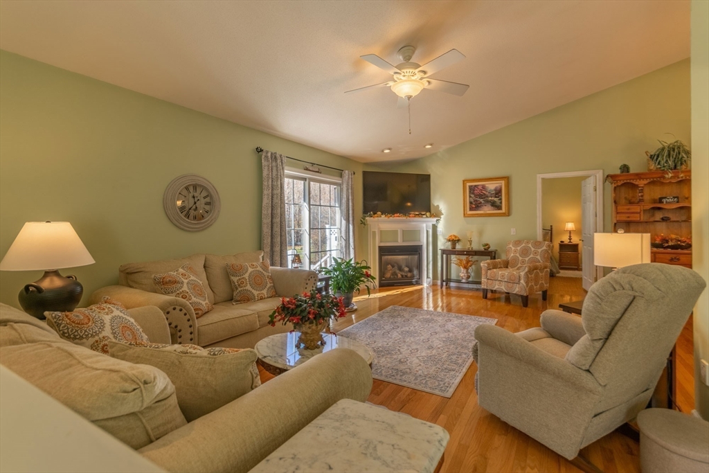 15 Michael Drive, Unit 15 Thorndike, MA 01079 - Photo 6 of 27 a living room with furniture a chandelier and a dining table with wooden floor