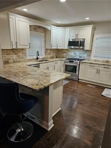 a kitchen with kitchen island granite countertop a sink cabinets and stainless steel appliances