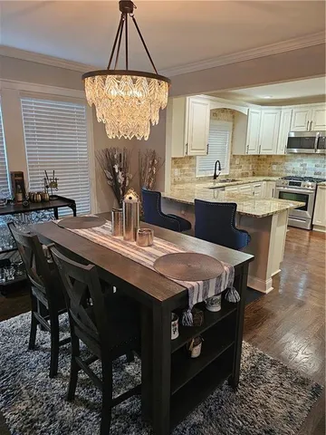 a kitchen with a table chairs sink and white cabinets