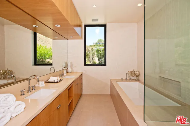 a bathroom with a tub double vanity sink and mirror