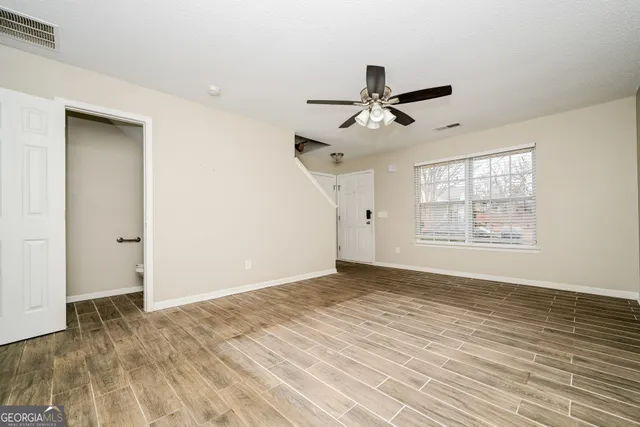 a view of empty room with wooden floor and fan