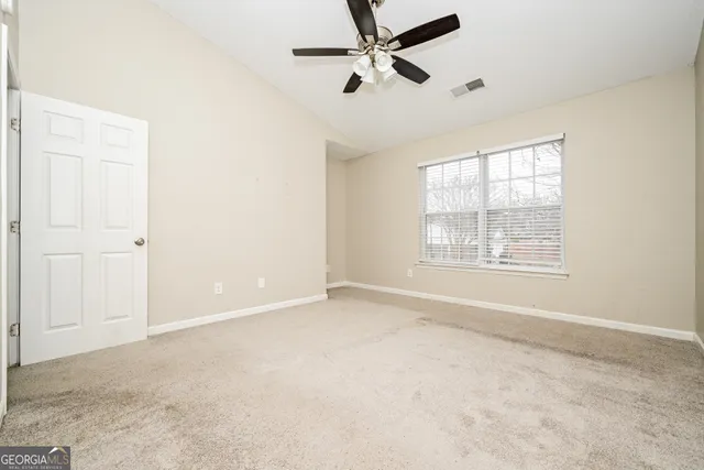 an empty room with fan and windows