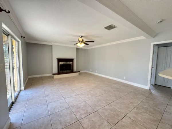 an empty room with a fireplace and chandelier fan