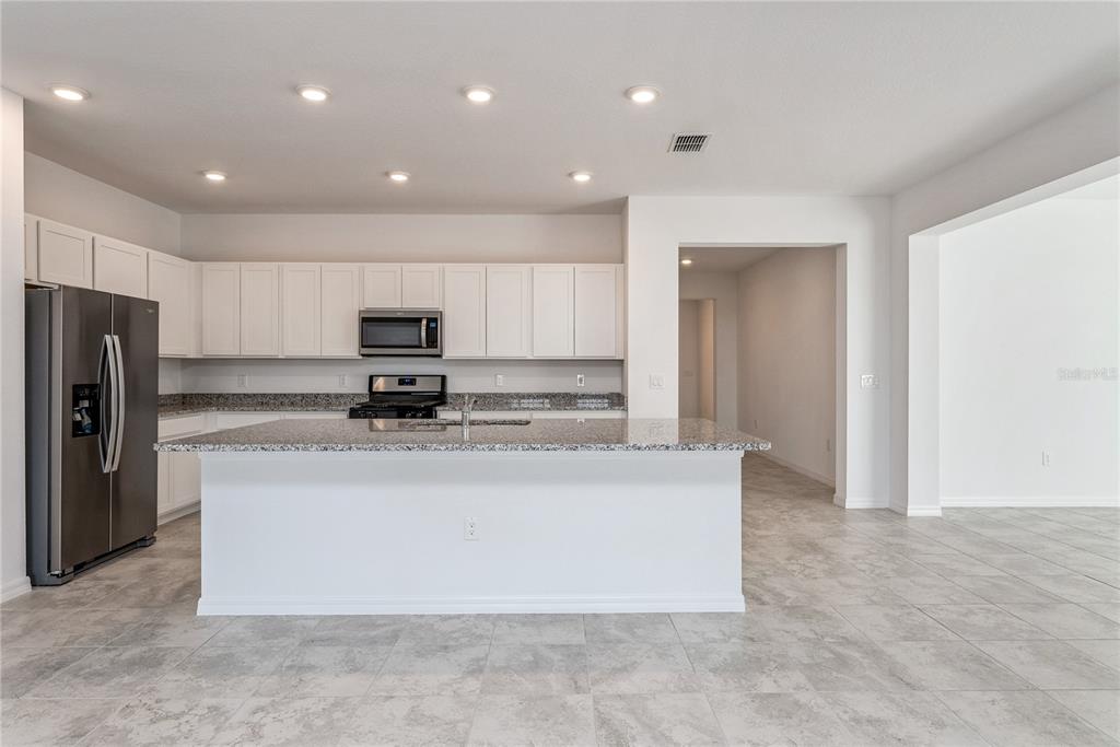 7405 Southwest 61st Street Ocala, FL 34474 - Photo 14 of 46 a large kitchen with stainless steel appliances granite countertop a stove a refrigerator a sink and a microwave