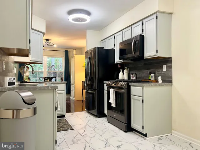 a kitchen with stainless steel appliances granite countertop a refrigerator a stove a sink dishwasher and white cabinets with wooden floor