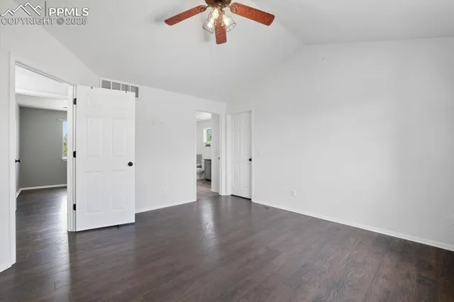 an empty room with wooden floor chandelier fan and windows