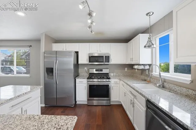 a kitchen with stainless steel appliances granite countertop a refrigerator a sink dishwasher a stove with wooden cabinets and floor