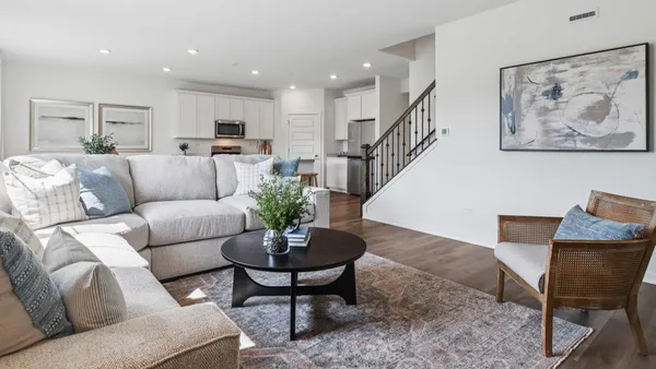 a living room with furniture potted plant and kitchen view