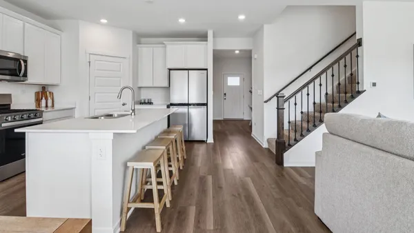 a kitchen with stainless steel appliances kitchen island granite countertop a stove a sink a refrigerator and white cabinets with wooden floor