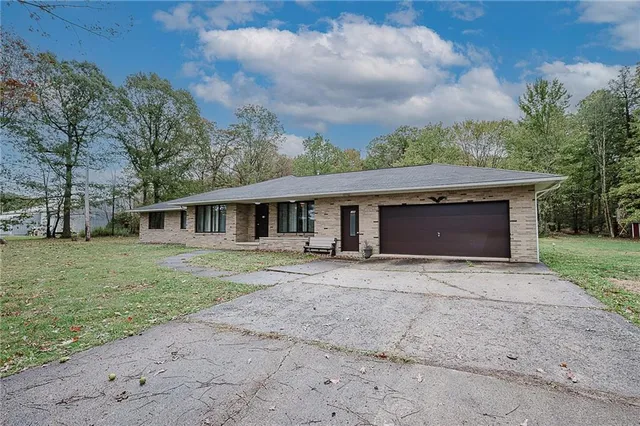 a front view of a house with a garden and trees