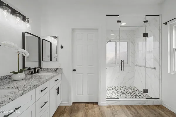 a bathroom with a granite countertop sink two mirror and shower