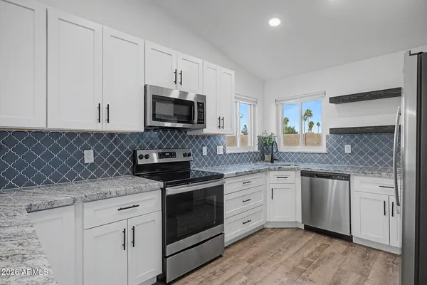 a kitchen with granite countertop white cabinets white stainless steel appliances and a sink