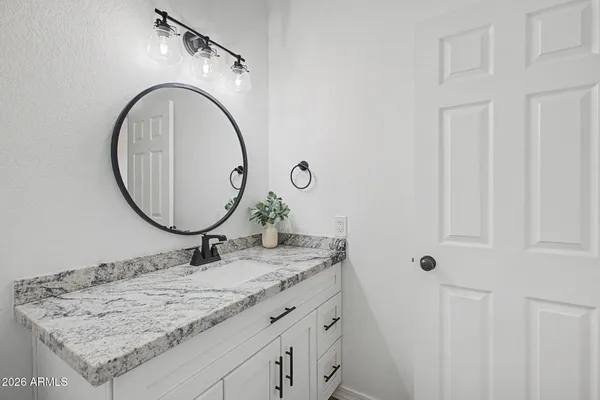 a bathroom with a granite countertop sink a mirror and a shower