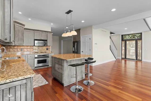 a kitchen with stainless steel appliances granite countertop a stove oven and a wooden floors