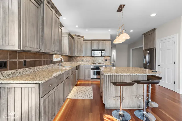 a kitchen that has a lot of cabinets in it with stainless steel appliances granite countertop a stove a sink and a refrigerator