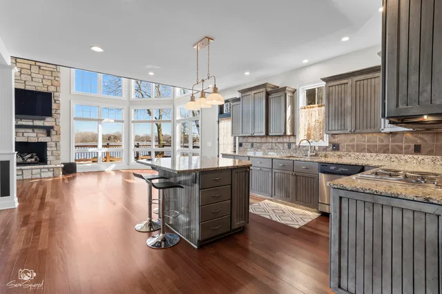 a kitchen with stainless steel appliances granite countertop a stove top oven a sink with wooden floors and cabinets