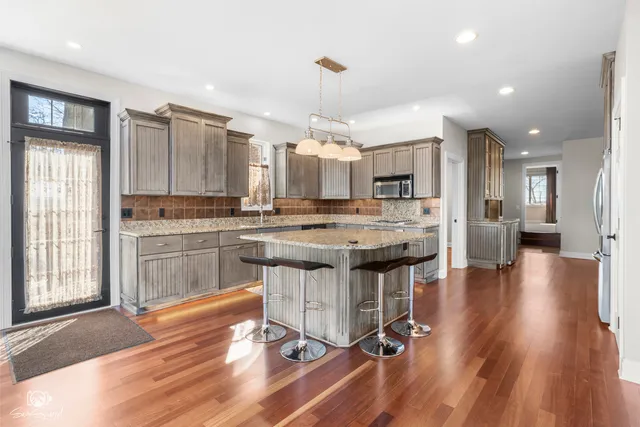 a kitchen with kitchen island granite countertop a sink cabinets and wooden floor
