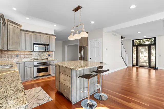 a kitchen with granite countertop a stove top oven a sink dishwasher a dining table and chairs with wooden floor