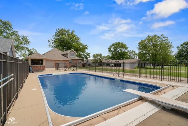 a view of swimming pool with seating area and trees in the background