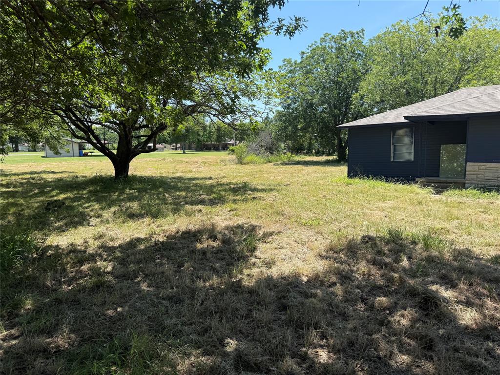 560 West New Hope Road West New Hope, TX 75071 - Photo 7 of 7 Expansive lot featuring a mature tree, natural grass, a dark-toned exterior facade, and a stone accent foundation