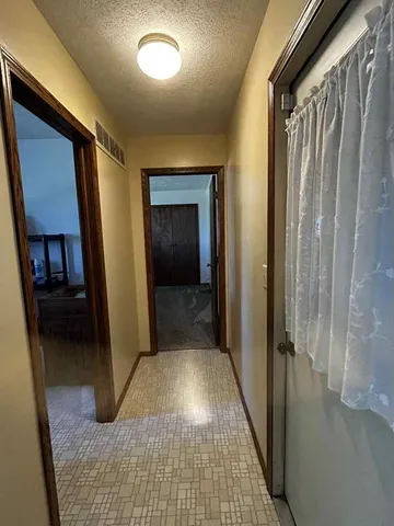 a view of a hallway with wooden floor and a living room