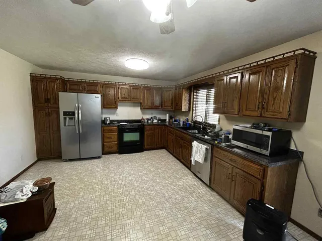 a kitchen with stainless steel appliances granite countertop a refrigerator a stove a sink a microwave and wooden cabinets