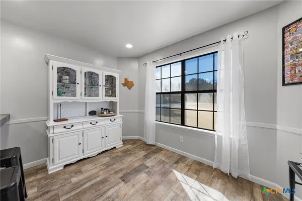 a kitchen with granite countertop a refrigerator oven a sink dishwasher and white cabinets next to a window