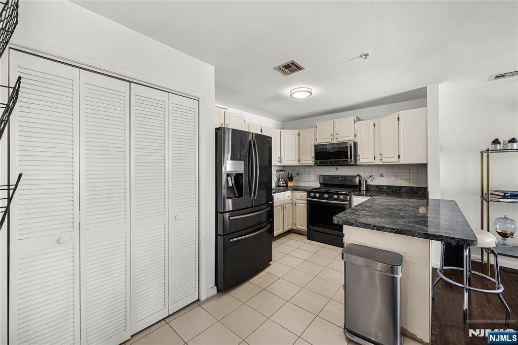 84 Union Street Newark, NJ 07105 - Photo 16 of 39 a kitchen with white cabinets and stainless steel appliances
