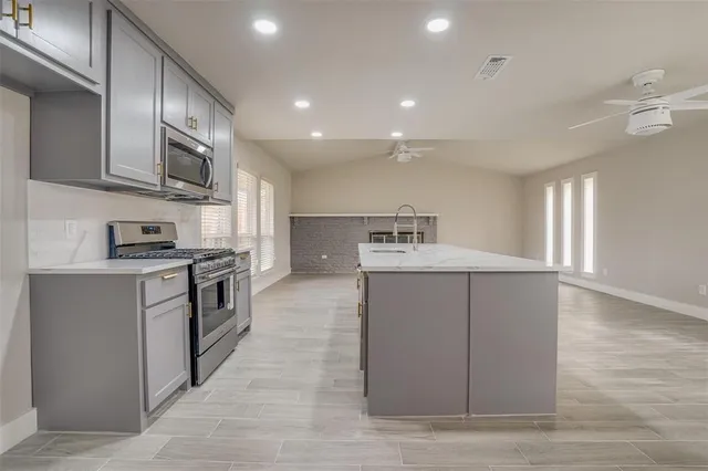 a kitchen with kitchen island granite countertop a stove sink and microwave