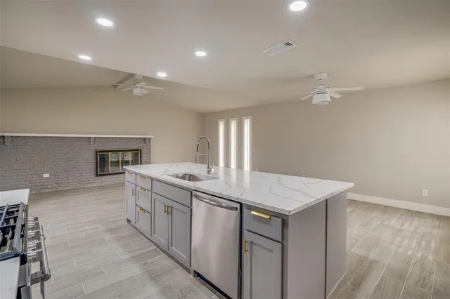 a large kitchen with a large counter top a sink stainless steel appliances and window