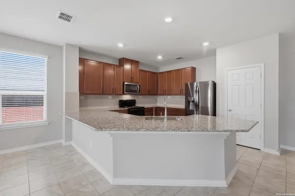 a large kitchen with stainless steel appliances granite countertop a sink and a refrigerator