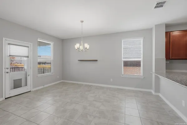an empty room with chandelier fan and windows