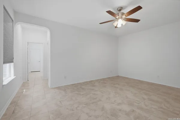 an empty room with a chandelier fan and windows